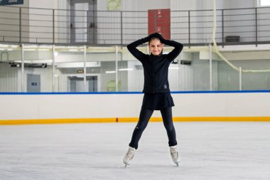 Genç kız artistik patinajcı kapalı bir buz pateni pistinde antrenman yapıyor..