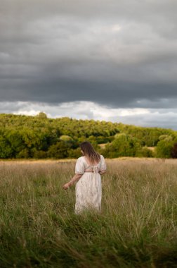 Fırtınadan önce uzun otların üzerinde duran bir kadın. Arka plan.