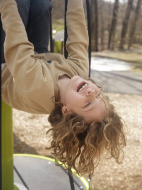 Oyun bahçesinde uzun saçlı genç bir çocuk.