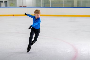 Erkek artistik patinajcı, kapalı alanda paten kayar ve yeteneğini gösterir..