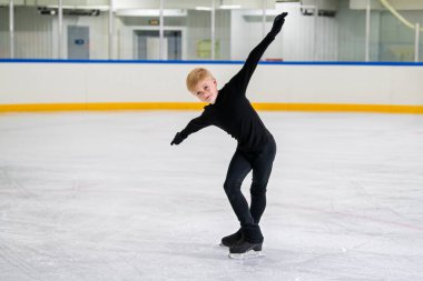 Erkek artistik patinajcı, kapalı alanda paten kayar ve yeteneğini gösterir..