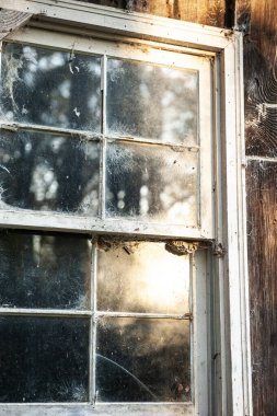Kırsal bir kulübenin duvarında kirli bir pencere var..