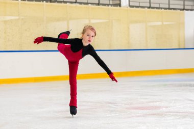 Genç bir kız artistik patinajcı buz üzerinde bir element üzerinde çalışıyor..