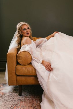 Oturma odasındaki kanepede peçeli ve gelinlikli sarışın gelin.