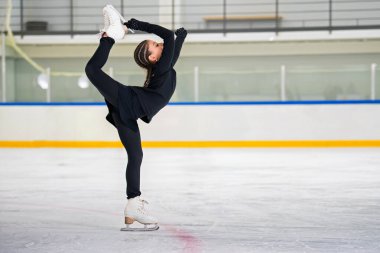 Genç kız artistik patinajcı buz üzerinde esnekliğini gösteriyor..