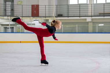 Genç bir kız artistik patinajcı buz üzerinde bir element üzerinde pratik yapıyor..