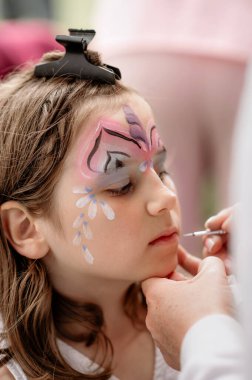 Yüz boyama işlemi devam ediyor. Genç bir kızın portresinin yakın çekimi..