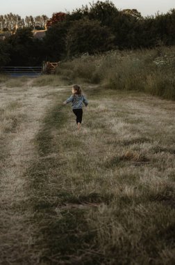 Küçük kız çimenlerde koşuyor..