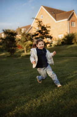 Bir kız parkta çimlerin üzerinden koşuyor. İlkbahar.
