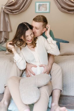 Mutlu hamile kadın ve erkek sarılıp gülüyor.