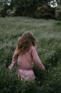 Kız yüksek / uzun otların arasından geçer.