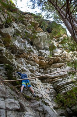 Gençlik, çam ormanlarıyla çevrili dik kayalıklara tırmanıyor.