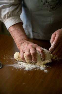 Un kaplı masada hamur yoğuran yaşlı kadın