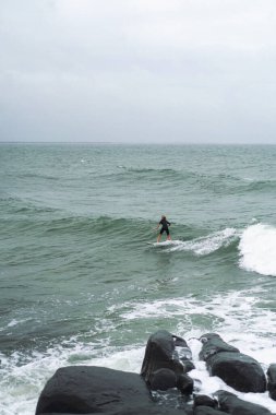 Çocuk Avustralya 'da okyanus dalgalarında sörf yapıyor.