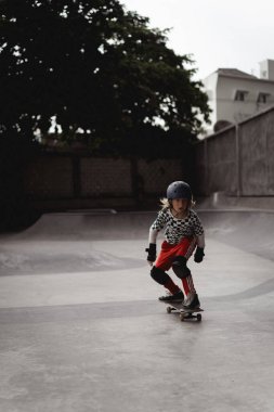 Kaykay yapan bir çocuk kaykay parkında eğleniyor.
