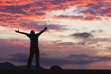 Gün batımında kutlama yapan birinin silueti.