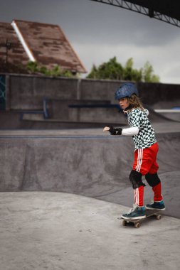 Kaykay yapan bir çocuk kaykay parkında eğleniyor.