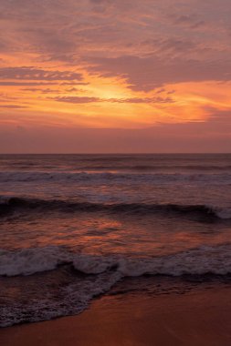 Dalgalar ve dramatik bulutlarla canlı okyanus batımı