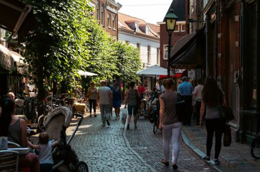 Kafeler, ağaçlar ve yürüyen insanlarla dolu bir Hollanda caddesi.