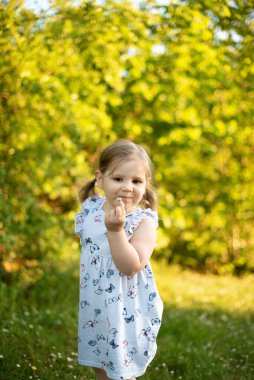 Gülümseyen kız yüzünün yanında papatya çiçeği tutuyor..
