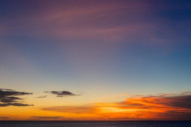 Sahilde insanlarla okyanusun üzerinde canlı bir gün batımı.