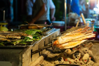 Gece pazarında mangal kömürü üzerinde ızgara balık pişirme