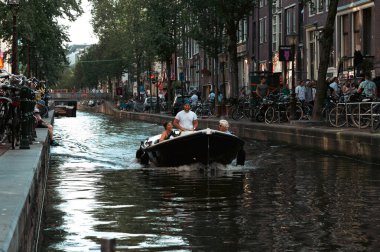 Üç kişi teknede Amsterdam Kanalı 'nda, şehir zemininde.
