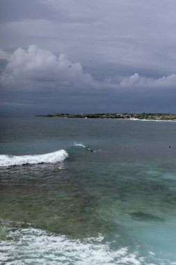 Bulutlu gökyüzünün altında bekleyen sörfçüler