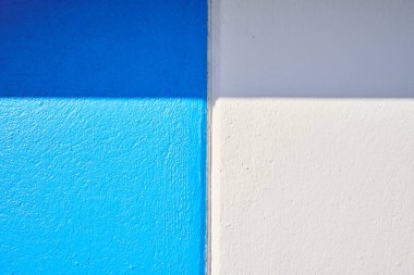 Güneş ışığı mavi ve beyaz duvarda gölge yaratıyor