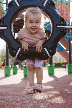 Küçük kız oyun parkında oynarken gülümser.