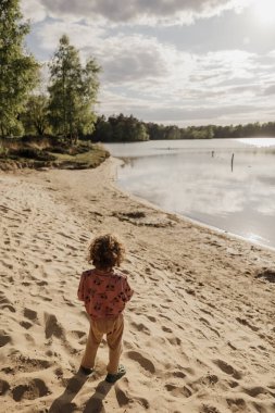 Çocuklar kumlu bir göl kıyısında yumuşak altın güneş ışığı altında