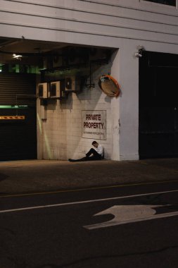 Resmi kıyafetli bir adam geceleri tek başına şehir caddesinde oturuyor.