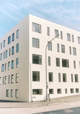 Birçok penceresi ve park edilmiş bisikleti olan beyaz minimalist bina