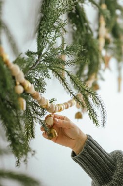 Boncuklu çelenk takan küçük pirinç bir çanı tutan kadın.