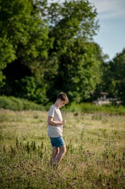 Çimenli bir çayırda tek başına duran bir çocuk yaz günü boyunca.