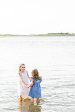 İki genç kız el ele tutuşup sığ okyanusta oynuyorlar. Cape Morinası