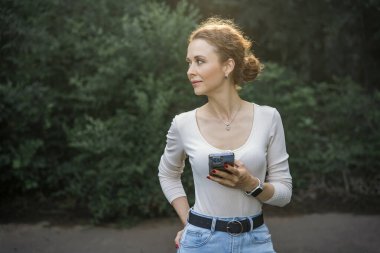 Telefonunu kullanan, gülümseyen ve mesajlaşan bir kadın..