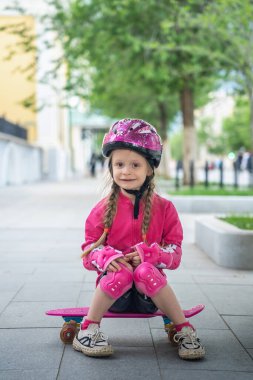 Parkta pembe kaykaylı küçük bir kız..