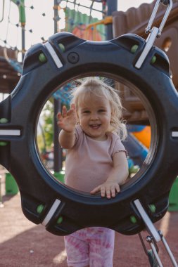 Oyun yapısındaki dairesel aralıktan el sallayan kız