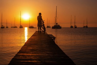 Gün batımında yelkenlilerle iskelede siluet