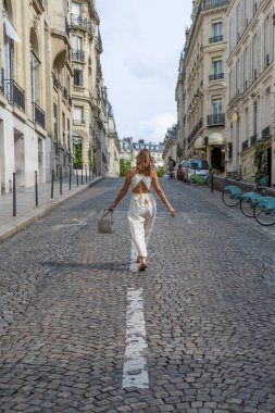Paris 'te büyüleyici bir kaldırım taşı caddesinde yürüyen zarif bir kadın.