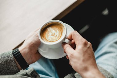 El ele tutulan Latte sanat kahvesi, üst manzara.