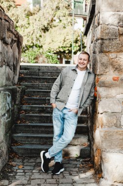 Sonbaharda yaşlı taş duvarda gülümseyen bir adam