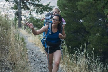 Annesi kasabanın dışında bir patikada yürür. Bebeğini sırtında taşır.