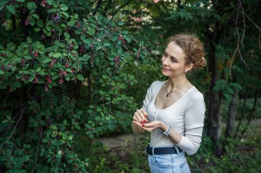 Ağaçtan böğürtlen toplayan bir kadın. Dışarıda, rahatlamış..