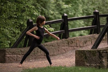 Küçük çocuk parkta klasik koreografi pratiği yapıyor..