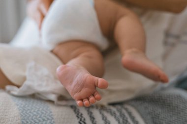 Beyaz bir beze sarılmış bir bebeğin ayaklarının yakın çekimi..