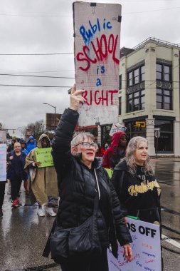 İki yaşlı kadın yağmurda işaretlerle protesto yürüyüşü yapıyor
