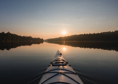 Kano önü Kanada 'da gün doğumunda gölün durgun sularına doğru ilerliyor..