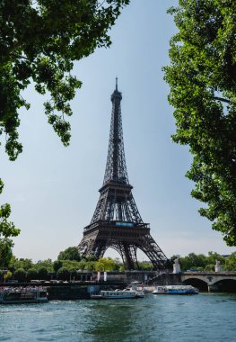 Paris, Fransa 'daki Seine kıyısındaki ağaçların arasından Eyfel Kulesi manzarası.
